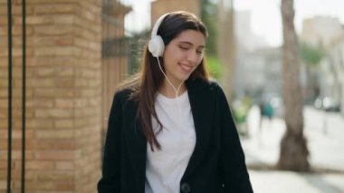 Genç İspanyol kız kendine güvenerek gülümsüyor müzik dinliyor ve sokakta dans ediyor.