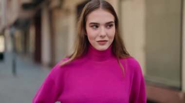 Young blonde woman standing with relaxed expression at street