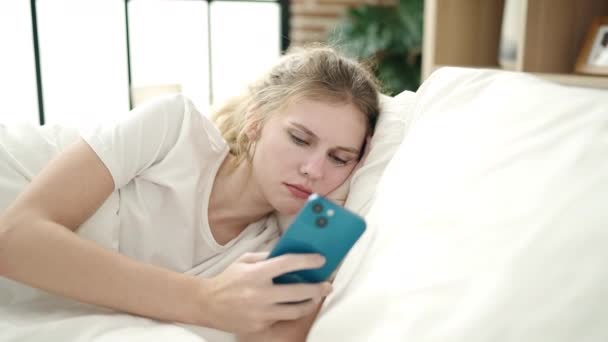 Jovem Loira Usando Smartphone Com Expressão Infeliz Quarto — Vídeo de Stock