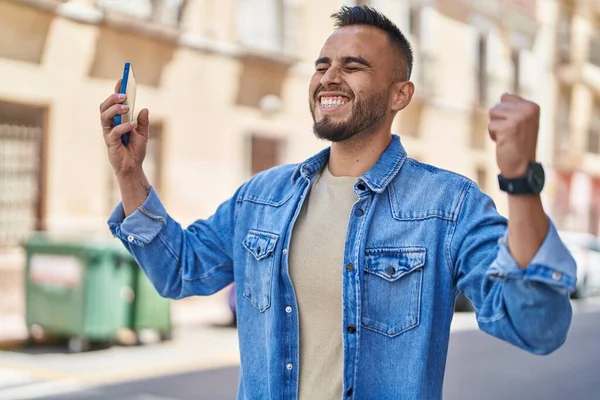 Jovem Hispânico Usando Smartphone Com Gesto Vencedor Rua — Fotografia de Stock