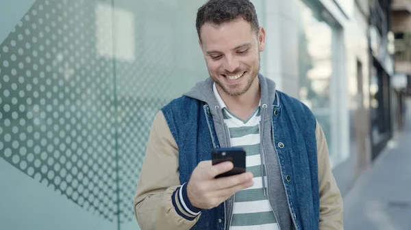 Νεαρός Καυκάσιος Άνδρας Χαμογελά Χρησιμοποιώντας Smartphone Στο Δρόμο — Φωτογραφία Αρχείου