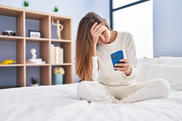 Yatak Odasında Endişeli Suratlı Akıllı Telefon Kullanan Genç Bir Kadın — Stok fotoğraf