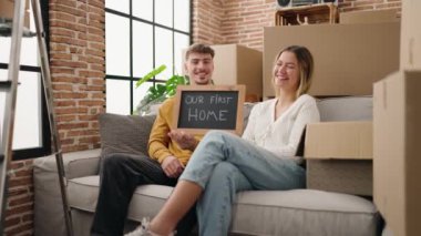 Young couple holding blackboard and doing heart symbol at new home