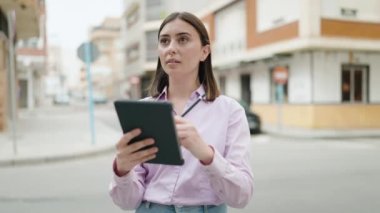 Young hispanic woman using touchpad at street