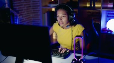 Young african american woman streamer playing video game with winner expression at gaming room
