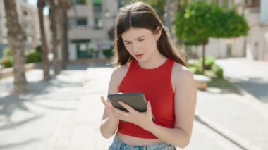 Young caucasian woman using touchpad with serious expression at park