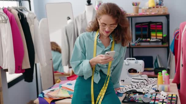 在裁缝店用智能手机裁缝店里年轻漂亮的惊慌失措女裁缝 — 图库视频影像