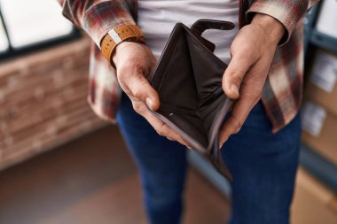 Young man showing empty wallet at office
