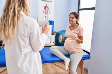 Genç Latin kadın hamile hasta klinikte fizyoterapi seansı yapıyor.