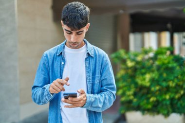 Genç İspanyol adam akıllı telefon kullanıyor. Sokakta ciddi bir ifadesi var.