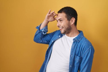 Sarı arka planda duran İspanyol adam mutlu ve gülümsüyor. arama kavramı. 