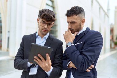 Two hispanic men business workers using touchpad working at street
