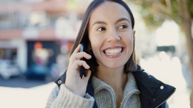 Young beautiful hispanic woman smiling confident talking on smartphone at street