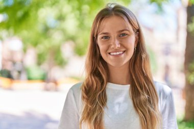 Young blonde girl smiling confident standing at park