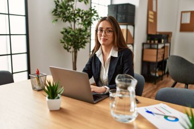 Ofiste çalışan genç İspanyol iş kadını laptopu kullanıyor.