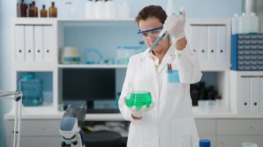 Laboratuvarda pipet kullanan orta yaşlı kadın bilim adamı üniforması giyiyor.
