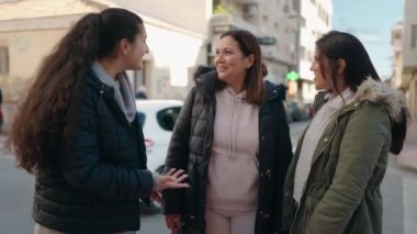 Anne ve kızları gülümsüyor, sokakta birbirlerine sarılıyorlar.