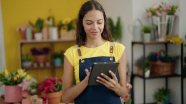 Young african american woman florist smiling confident using touchpad at flower shop