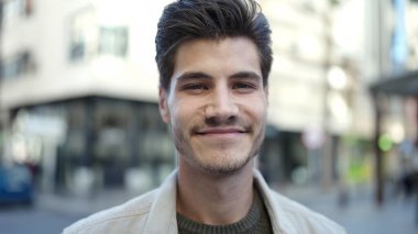 Sokakta kendinden emin gülümseyen İspanyol genç adam.