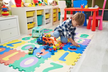 Tatlı İspanyol çocuk arabalarla oynuyor. Anaokulunda yerde oturuyor.