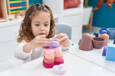 Sevimli sarışın çocuk anaokulundaki masada oyuncaklarla oynuyor.