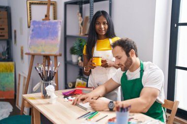 Man and woman artist couple drawing on notebook and drinking coffee at art studio