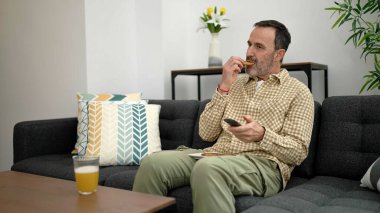 Middle age man watching movie having breakfast at home