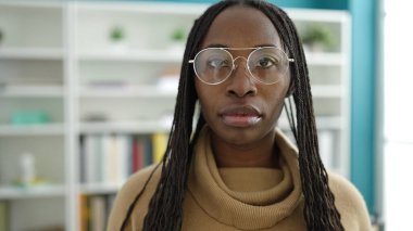 African woman standing with serious expression wearing glasses at library university