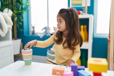Anaokulundaki masada oturan, inşaat bloklarıyla oynayan sevimli İspanyol kız.