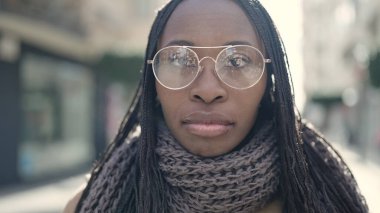 African woman standing with serious expression wearing glasses at street