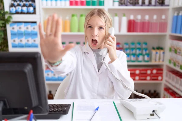 Young Caucasian Woman Working Pharmacy Drugstore Speaking Telephone Doing Stop — Foto Stock