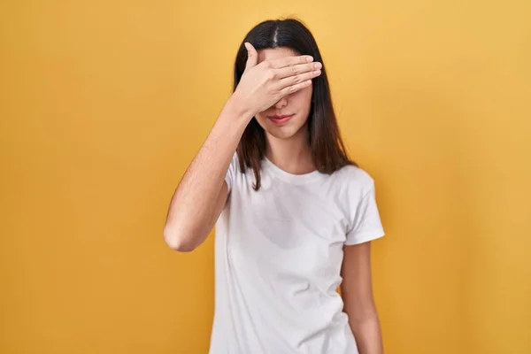 Young Beautiful Woman Standing Yellow Background Covering Eyes Hand Looking — Fotografia de Stock