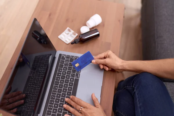 中年惊慌失措的女人在家里用信用卡和笔记本电脑买药 — 图库照片