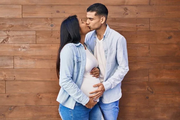 Young Latin Couple Expecting Baby Touching Belly Kissing Street — Stock fotografie
