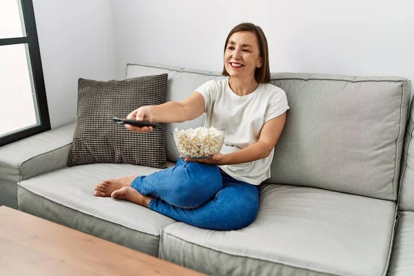 Střední Věk Hispánská Žena Sleduje Film Jíst Popcorn Doma — Stock fotografie