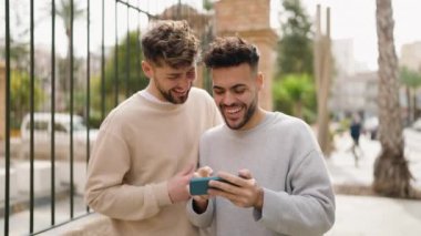 Young couple smiling confident using smartphone at street