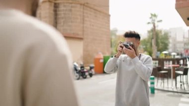 Genç çift sokakta profesyonel kamera kullanarak fotoğraf çekiyor.
