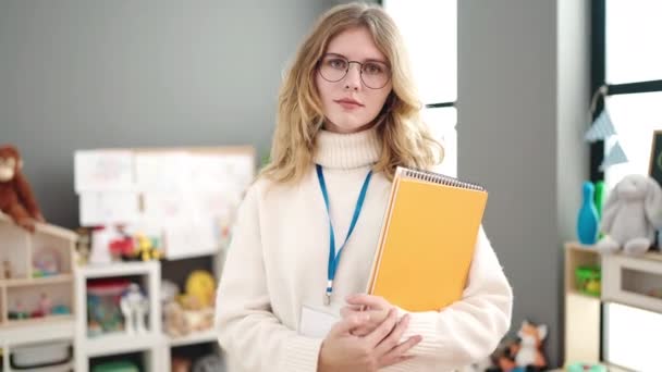 Young Blonde Woman Preschool Teacher Smiling Confident Holding Books Kindergarten — Video