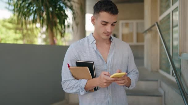 Молодий Студент Іспаномовного Чоловіка Використовуючи Смартфон Тримає Книги Вулиці — стокове відео