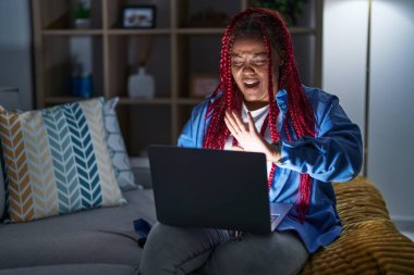 Saçları örgülü, bilgisayar laptopu kullanan Afrika kökenli Amerikalı bir kadın. El hareketlerini, öfke ve hayal kırıklığı ifadesiyle durduruyor. 