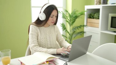 Young beautiful hispanic woman student using laptop studying at home