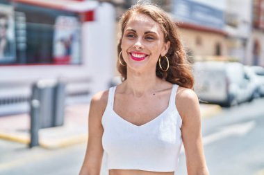 Young beautiful hispanic woman smiling confident looking to the side at street