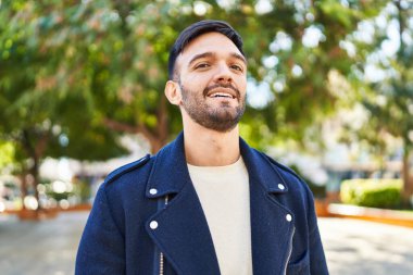 Parkta kendinden emin gülümseyen İspanyol genç adam.