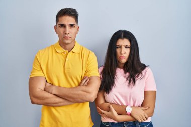 Young couple standing over isolated background skeptic and nervous, disapproving expression on face with crossed arms. negative person. 