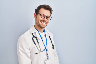 Doktor üniforması giyen genç İspanyol bir adam ve steteskop yüzünde gülümseme, doğal bir ifade ile yan yana bakıyor. Kendinden emin gülen. 