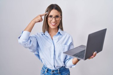 Young woman working using computer laptop smiling pointing to head with one finger, great idea or thought, good memory 