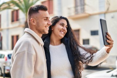Man and woman smiling confident having video call at street