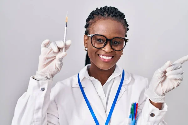 African Woman Braids Holding Syringe Smiling Happy Pointing Hand Finger — Stockfoto