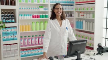 Genç Afrikalı Amerikalı kadın eczacı eczanede bilgisayar kullanarak gülümsüyor.