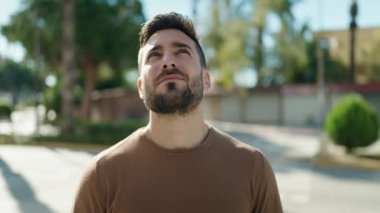 Young hispanic man smiling confident looking to the sky at park